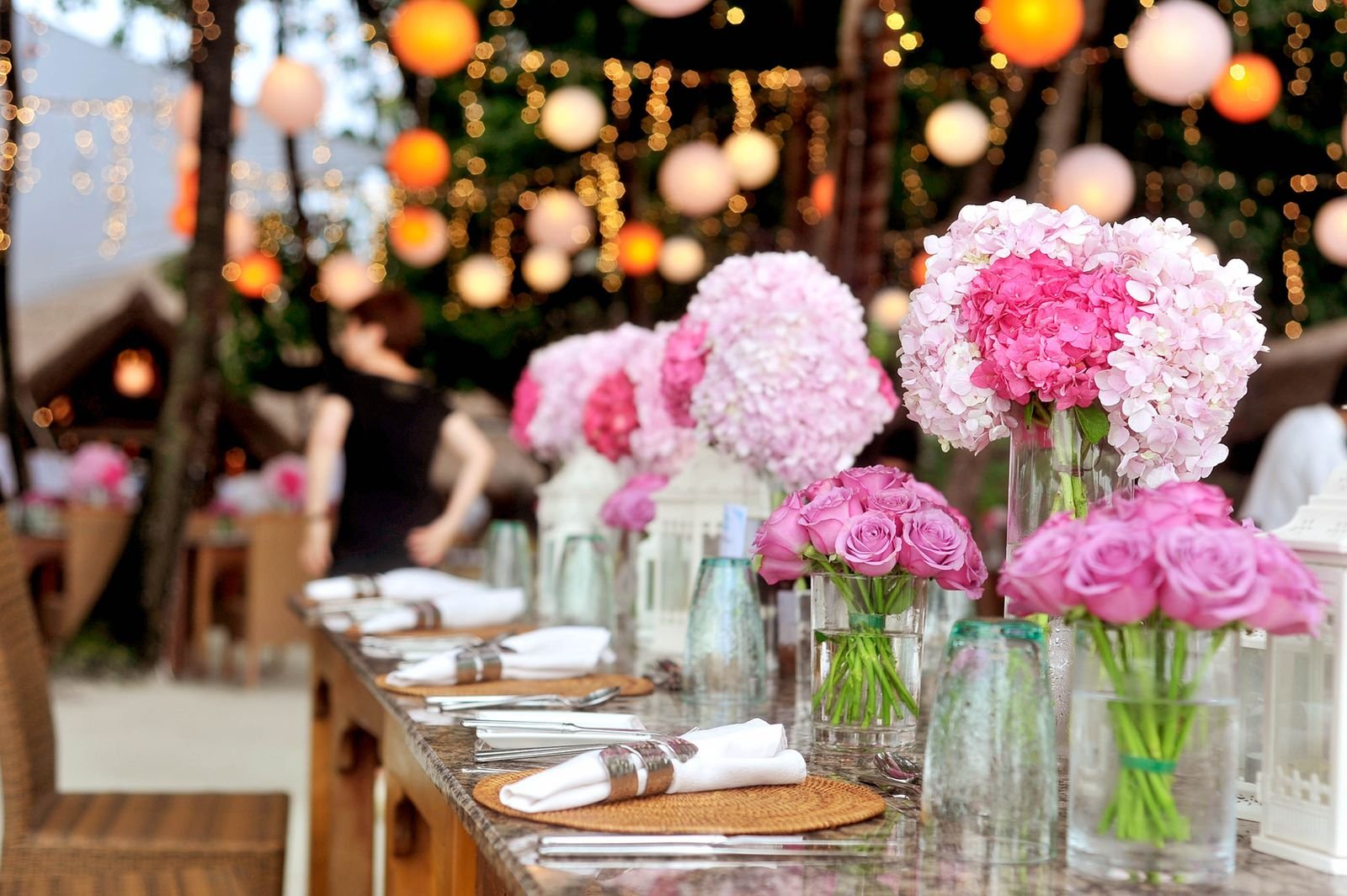A long wedding table set beneath lush garden trees